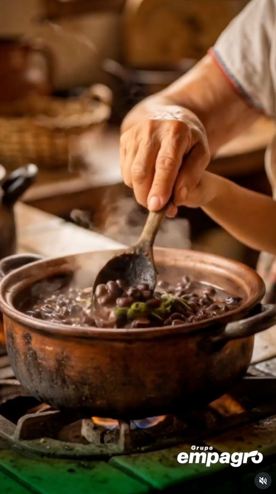 Manos de abuela cocinando frijoles en olla de barro